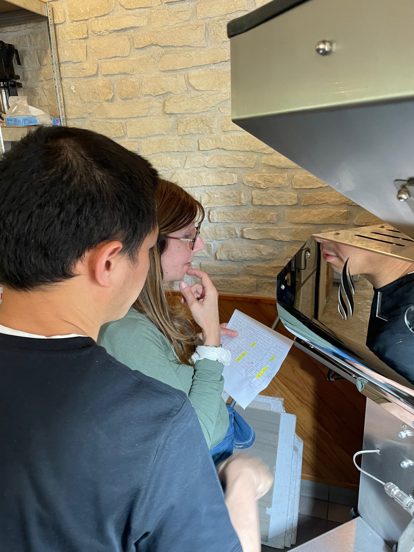 Members gathered around a professional roasting machine with a host member